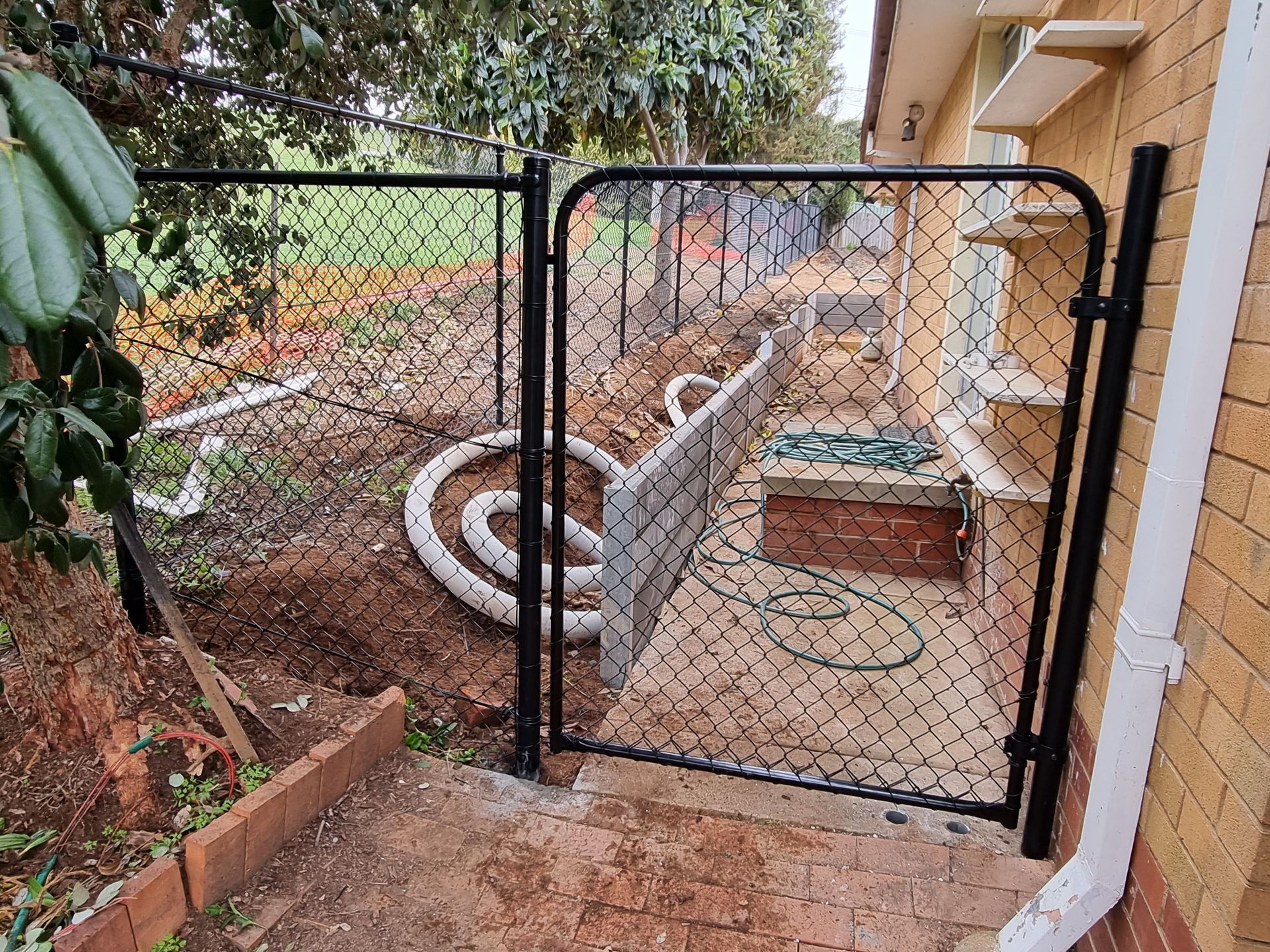 Freshly Constructed Retaining Wall with Tall Metal Fence and Clear Blue Sky in the Background — GnB Fencing and Excavation in Queanbeyan, NSW