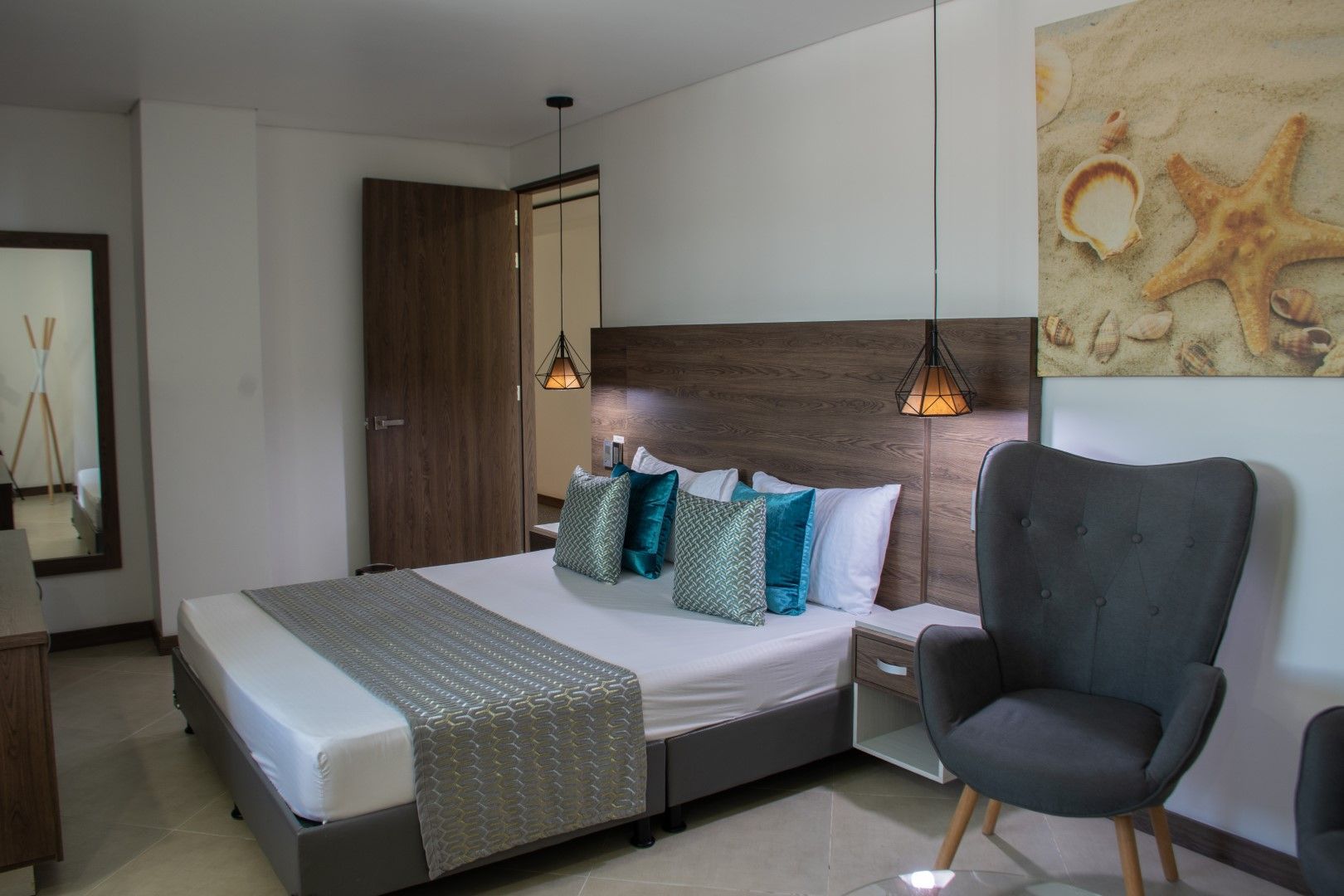 Un dormitorio moderno con una cama, una silla gris y una obra de arte de una estrella de mar en la pared.