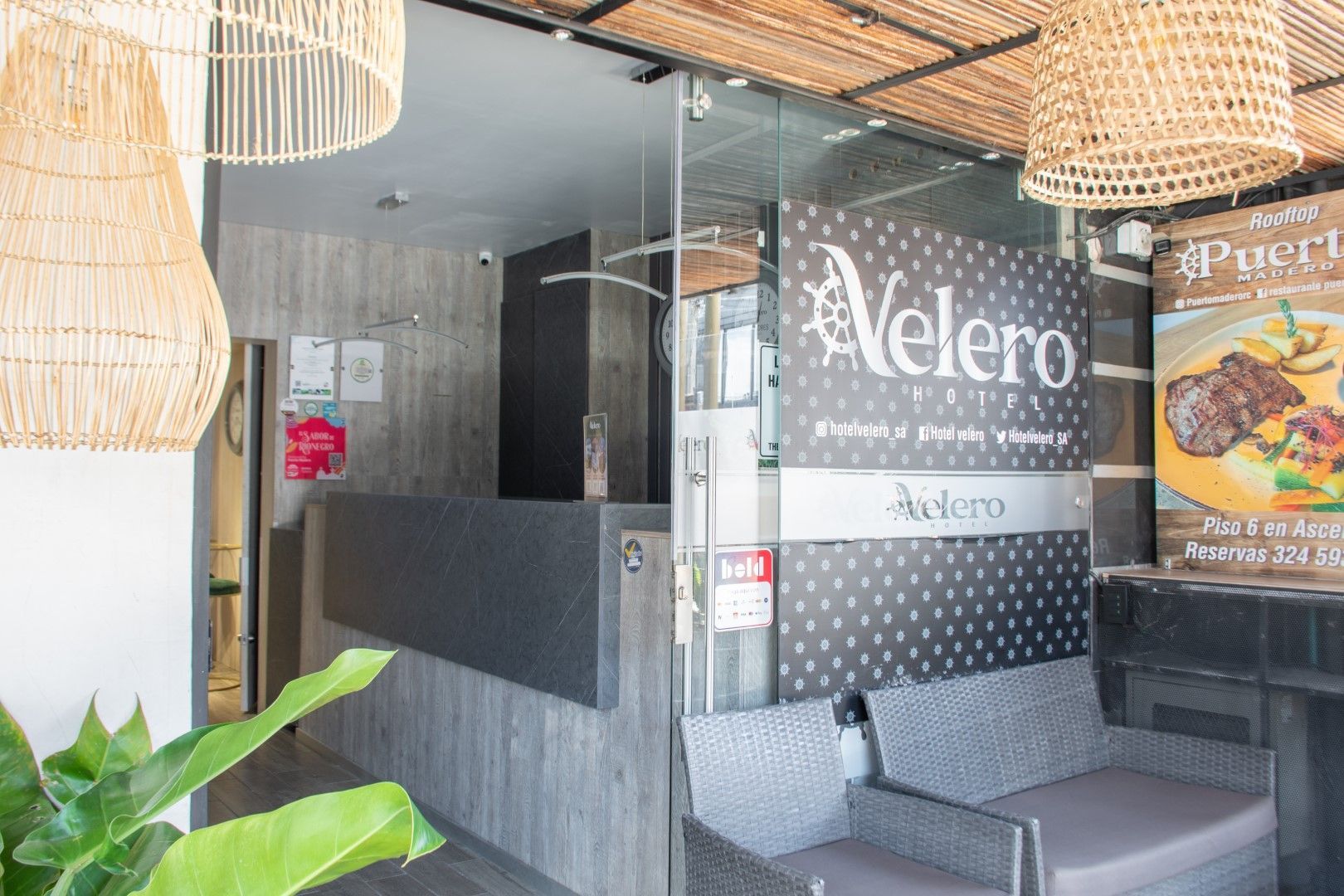 Entrada al restaurante Velero con mostrador de recepción, asientos y cartel.