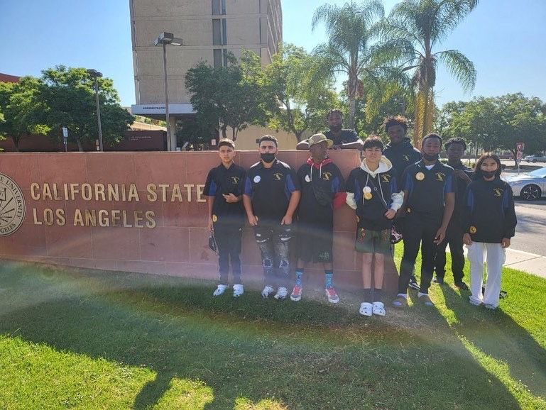 A group of people standing in front of a sign that says california state los angeles