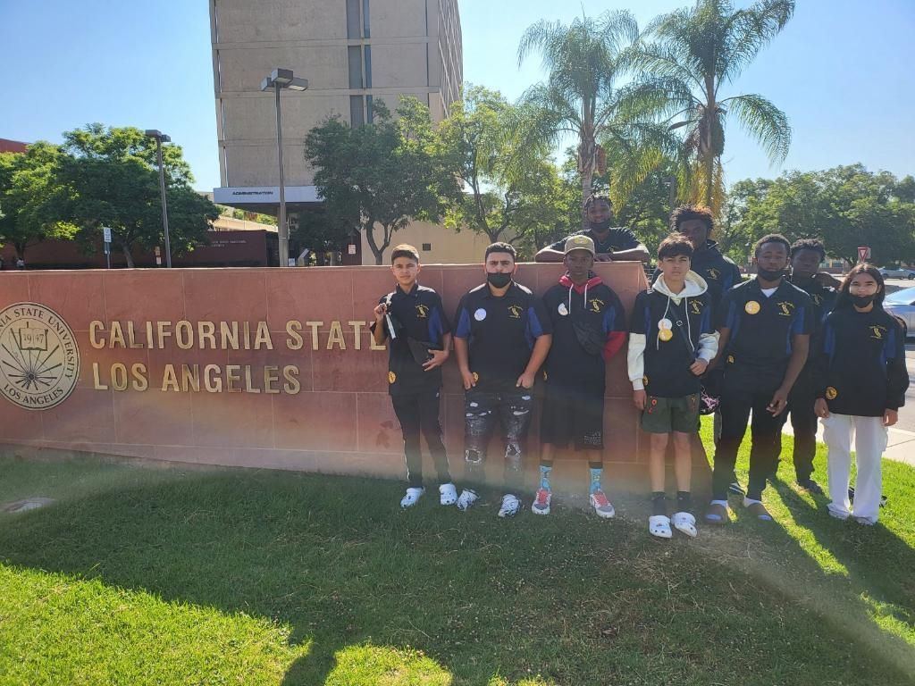 A group of people standing in front of a sign that says california state los angeles