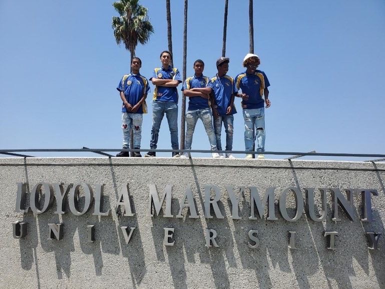 A group of people standing on top of a sign that says toyola marymount university