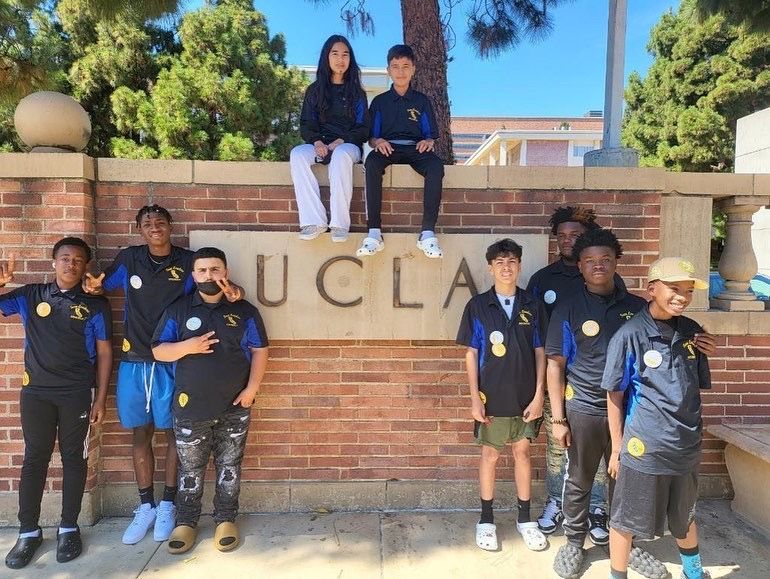A group of young people are posing for a picture in front of a sign that says ucla.
