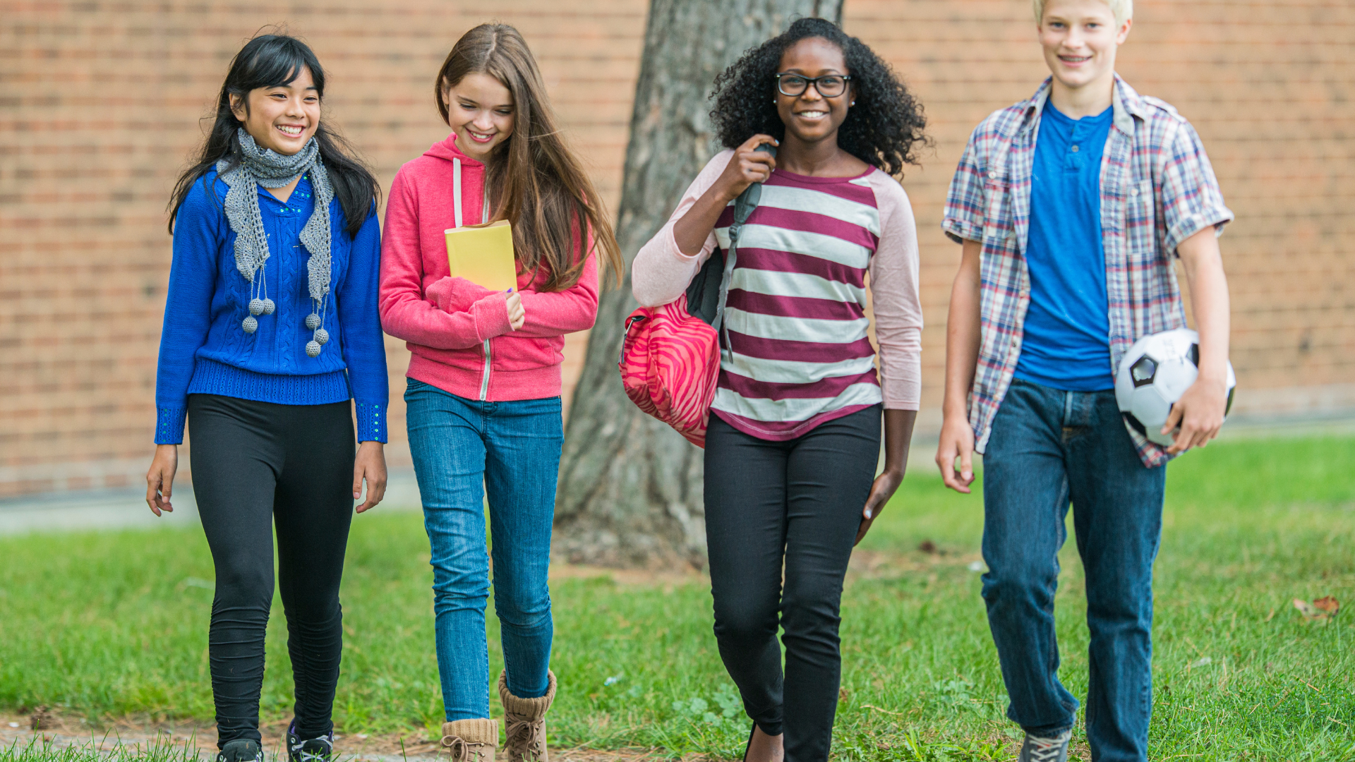 A group of young people are walking down a sidewalk.