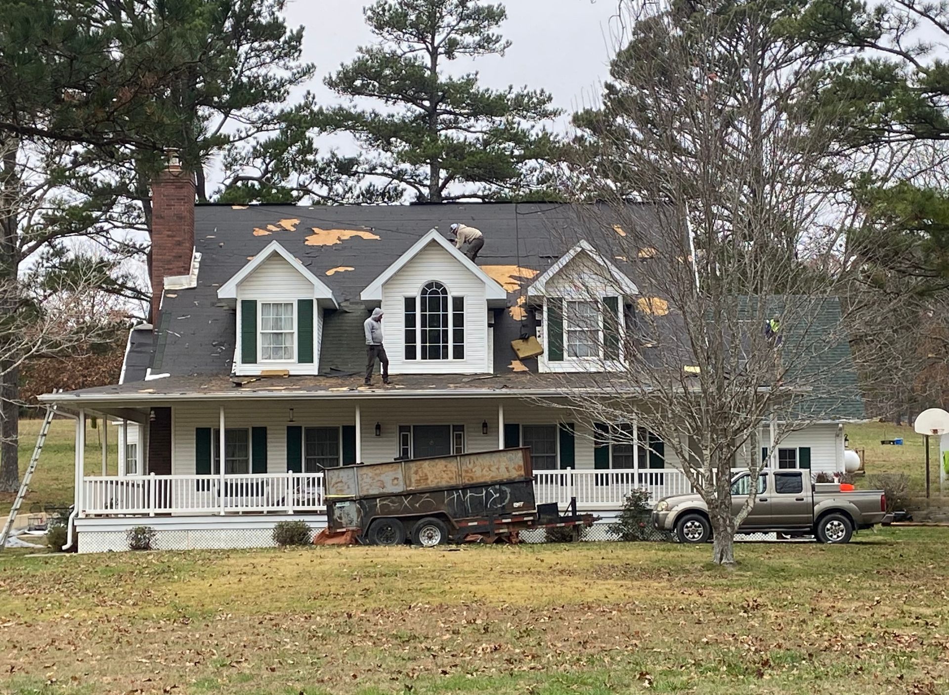 Roofers installing roofing material on a building with a red metal roof.