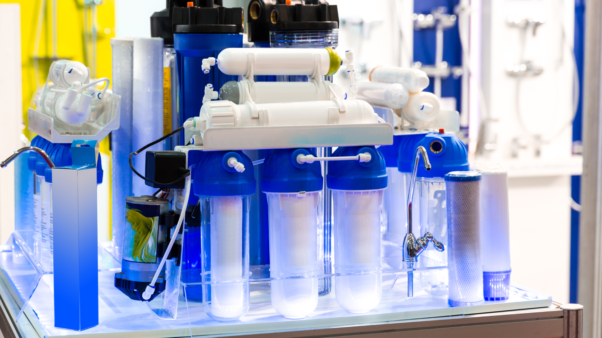 Blue-and-white industrial water filtration system with clear canisters on a workbench