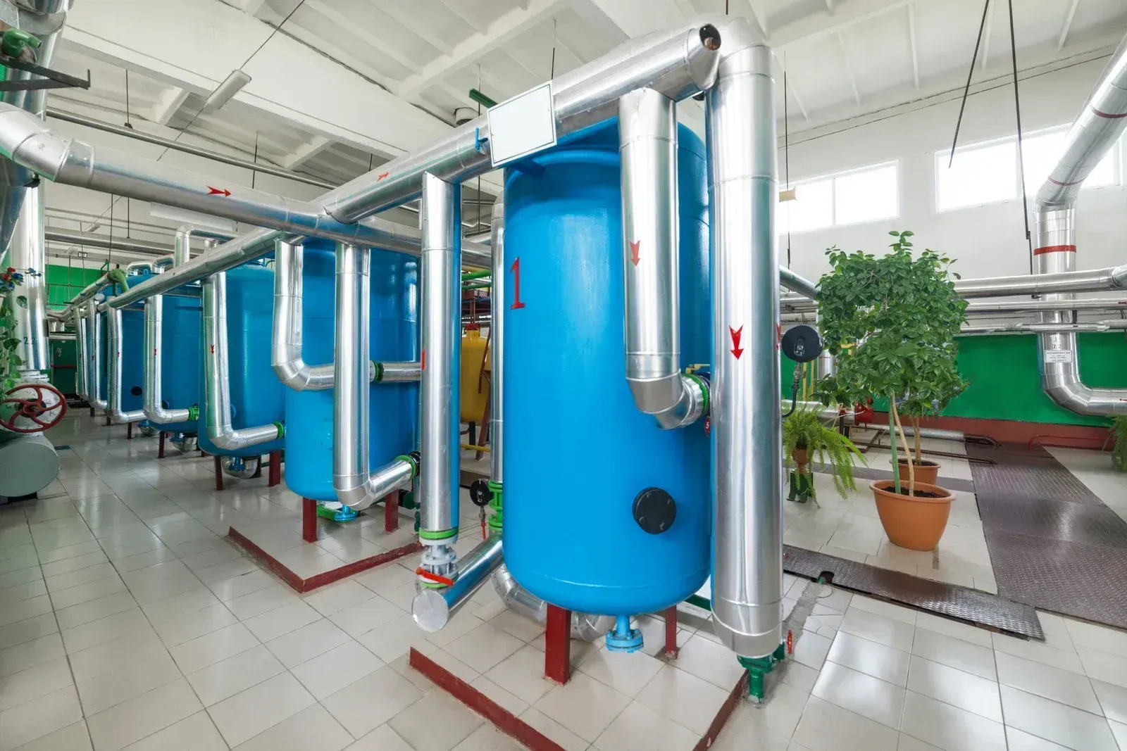 Large blue industrial tanks and pipes inside a bright factory room.
