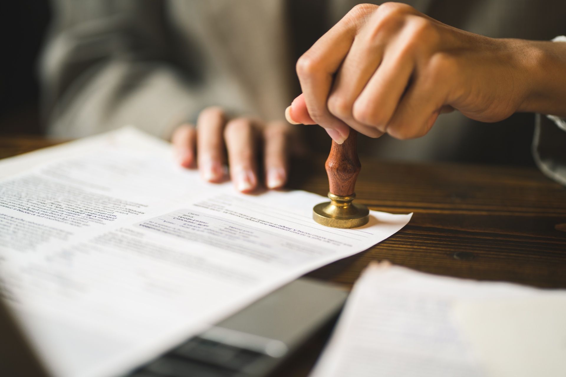 A person is stamping a document on a wooden table.