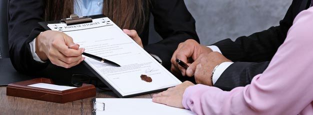 A man and a woman are sitting at a table signing a document.