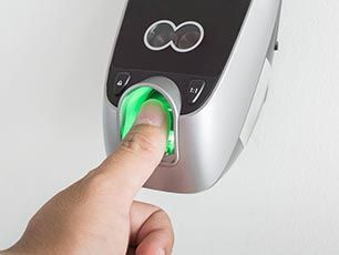 A person is pressing a green button on a fingerprint scanner.