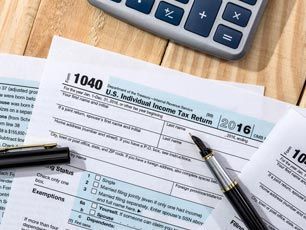 A pen is sitting on top of a tax form next to a calculator.