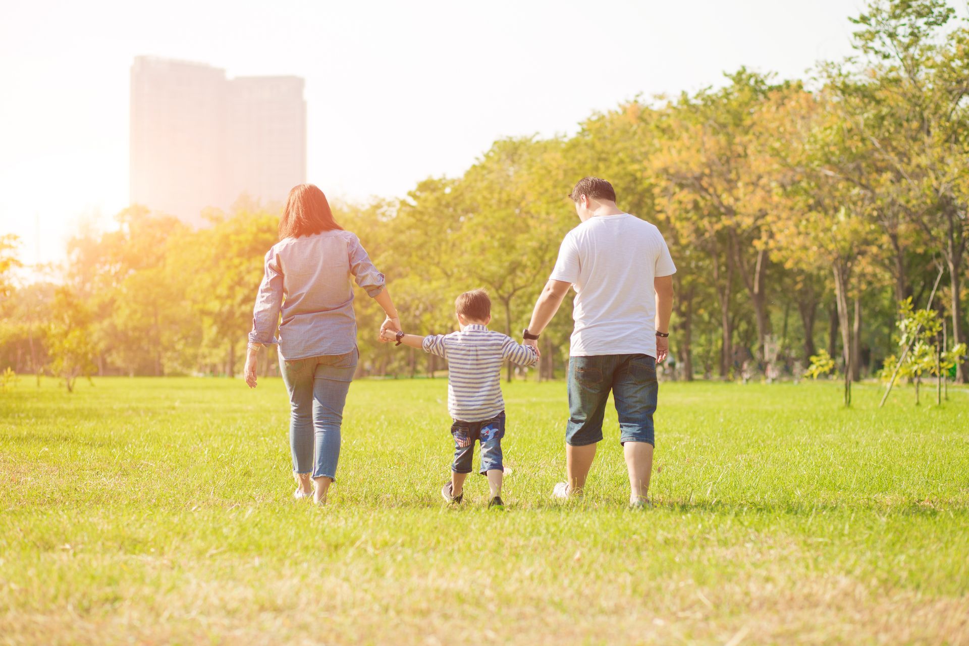 A family is walking through a park holding hands.