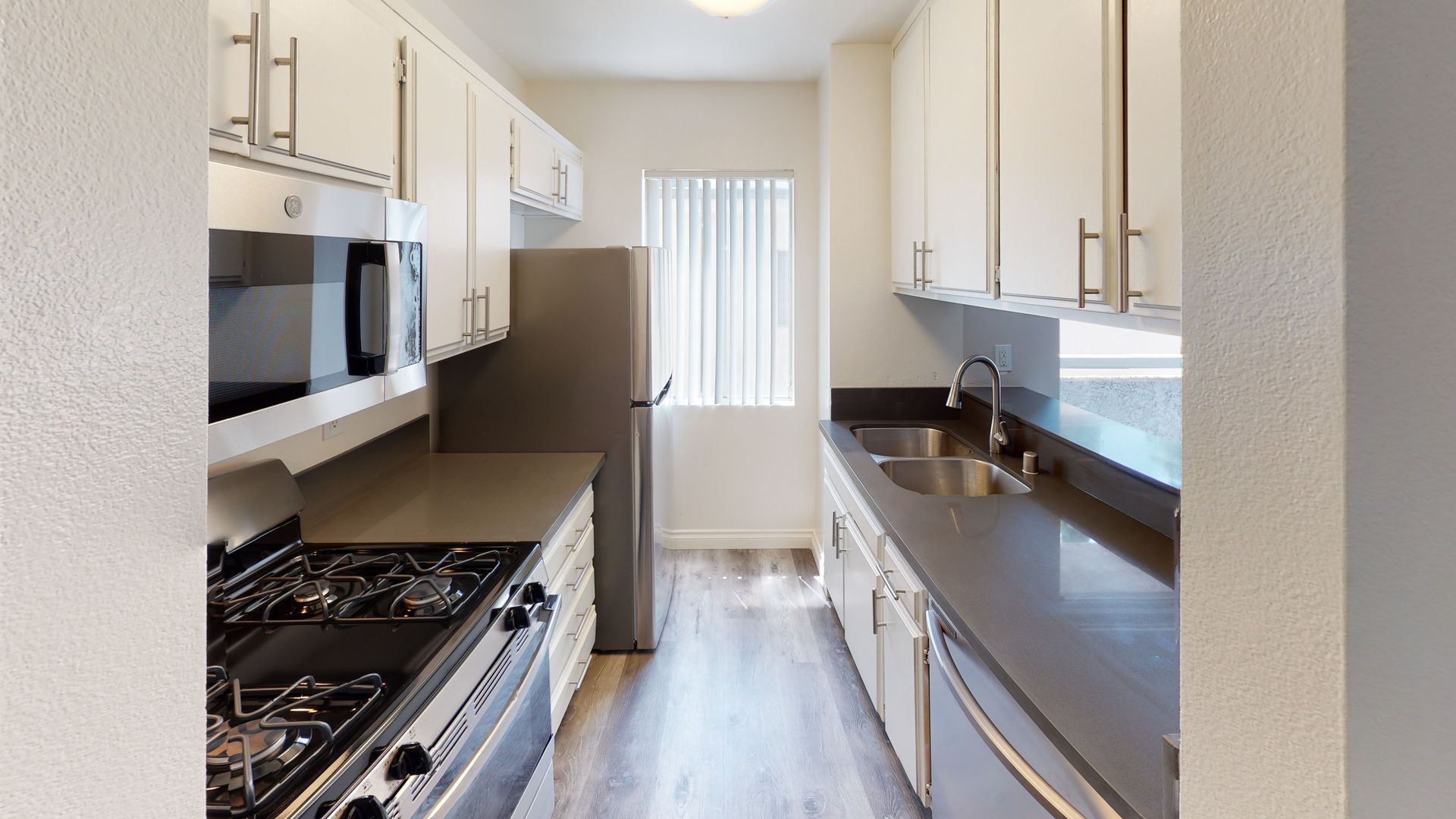 Kitchen with white cabinets, stainless steel appliances, and gray countertops.