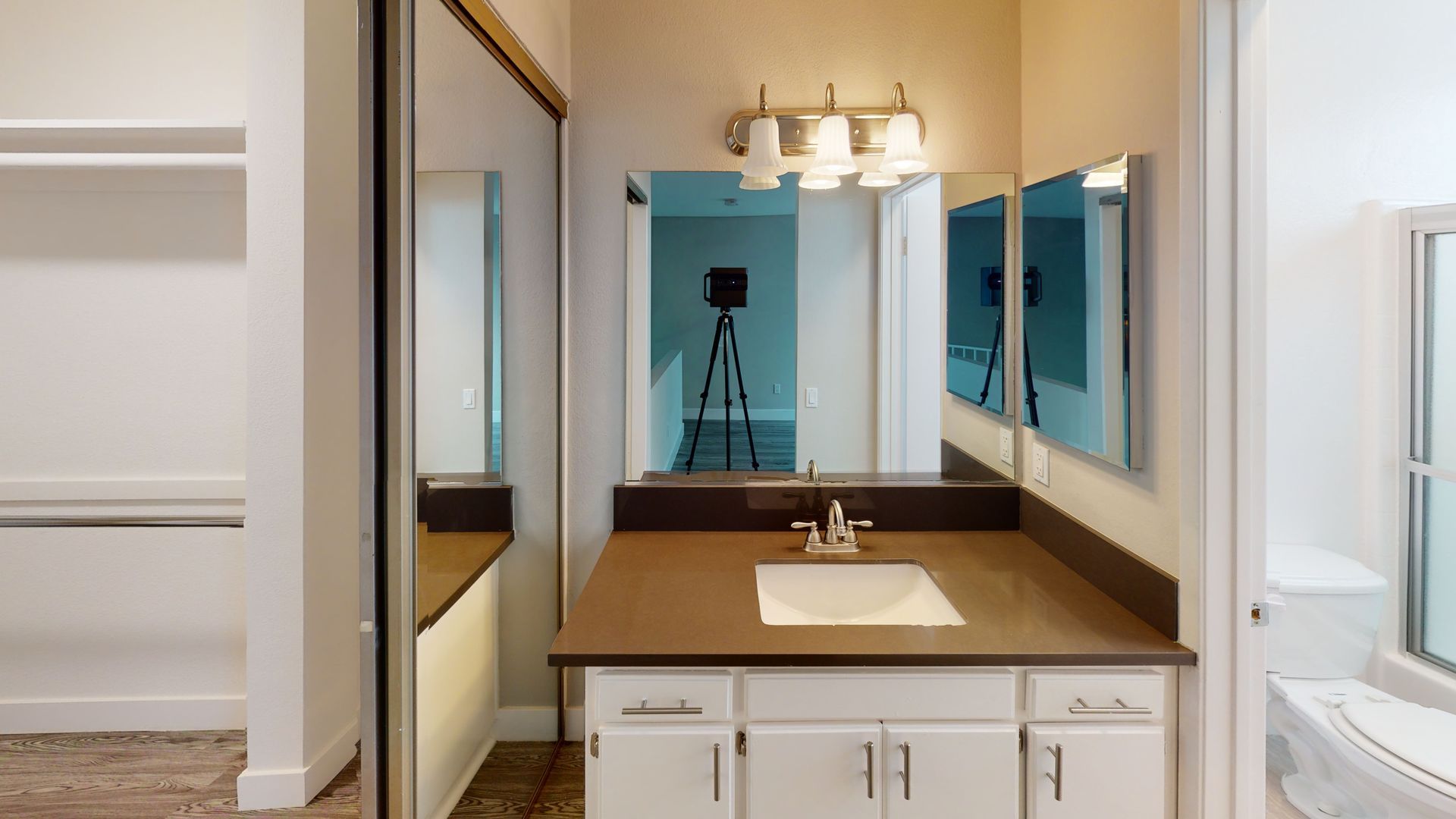 Bathroom with vanity, mirror, and white cabinets. A closet is visible on the left.