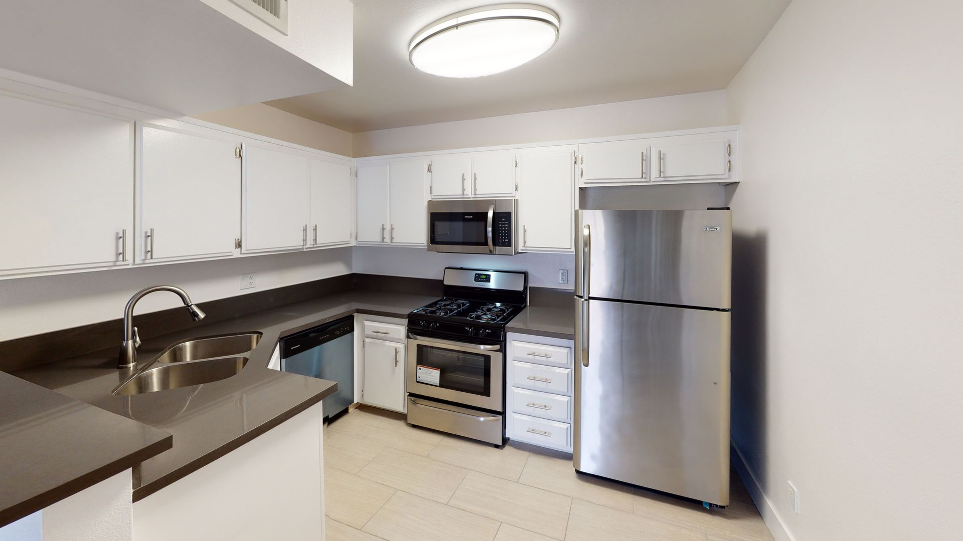 Kitchen with white cabinets, stainless steel appliances, and dark countertops.