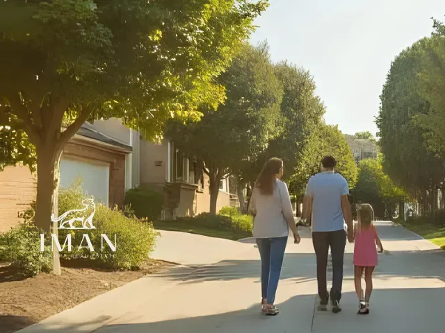 Family walking down a suburban street, holding hands. Sunny day, trees lining the sidewalk.