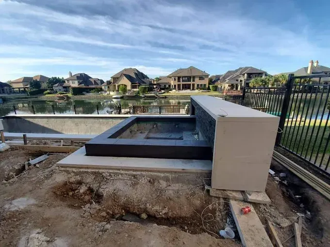 A fountain is being built next to a lake in a residential area.