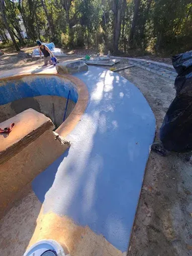 A person is painting a pool in the woods.