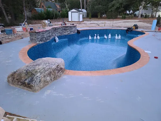 A large swimming pool is being built in a backyard.