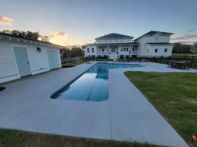 A large white house with a large swimming pool in front of it.