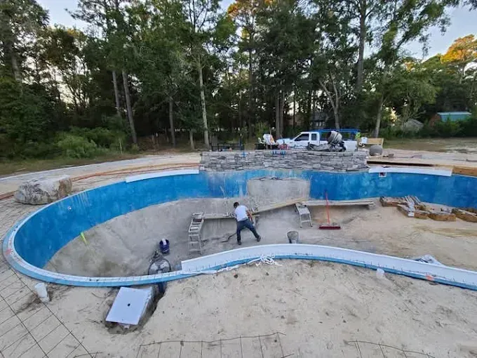 A large swimming pool is being built in a backyard.