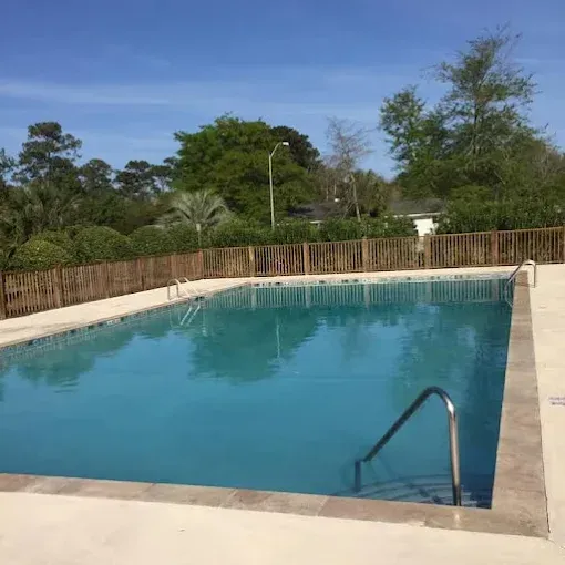 A large swimming pool with a wooden fence around it
