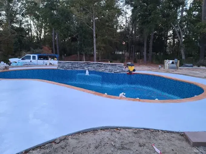 A large swimming pool is being built in the backyard of a house.