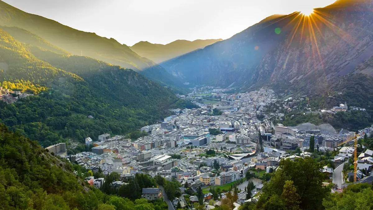 Una ciudad, andorra en medio de un valle rodeada de montañas con el sol brillando a través de los árboles. naturaleza