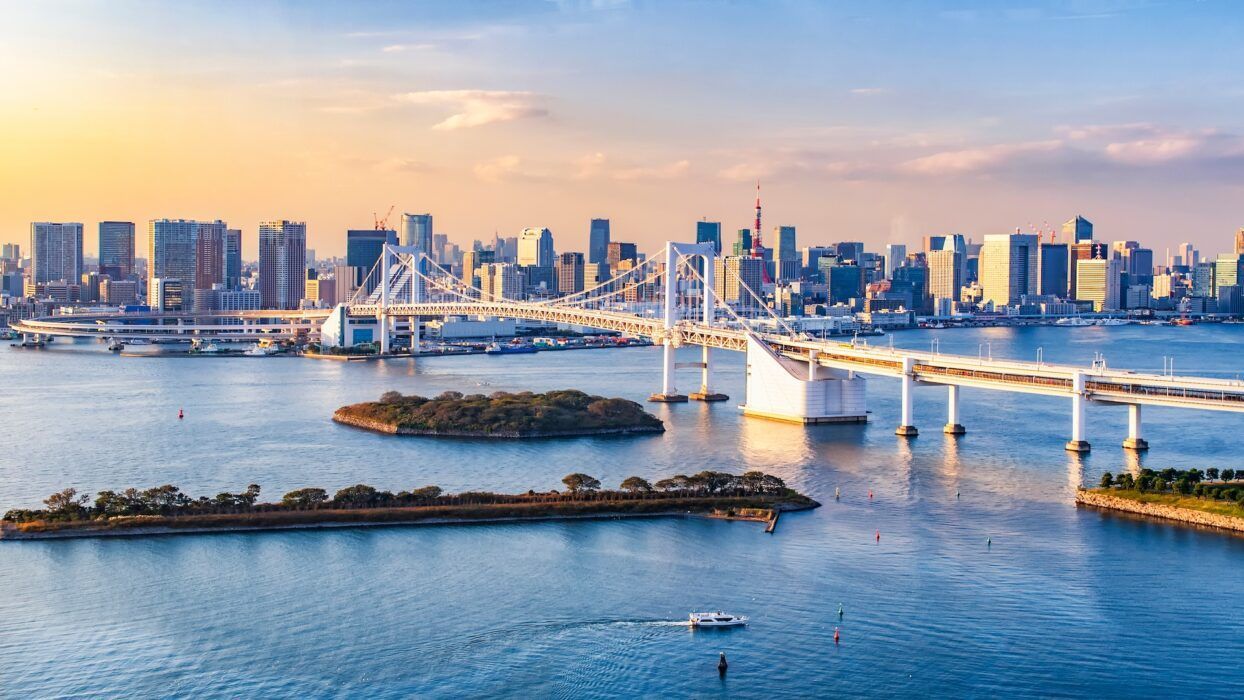 Una vista aérea de un puente sobre un cuerpo de agua con un horizonte de la ciudad en el fondo. japon vistas ciudad odaiba