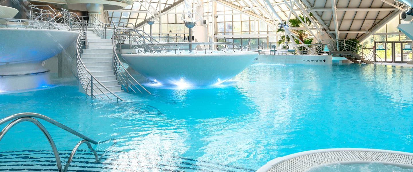 Hay una gran piscina en el medio de un edificio. caldea, agua relax, calma agua termal