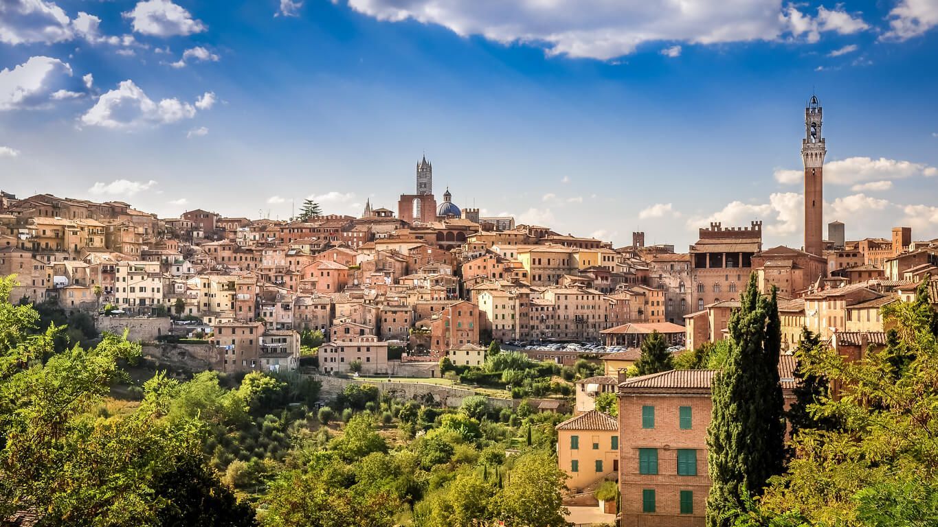 Una vista aérea de una ciudad rodeada de árboles y edificios de siena en italia. la toscana 