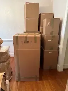 Person sealing a cardboard box with packing tape in a busy shipping area