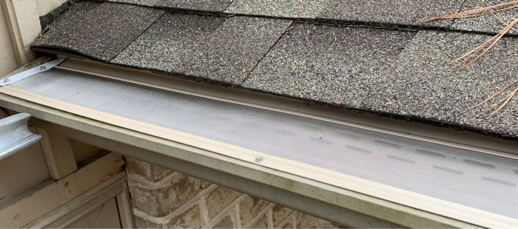 A gutter with a screen on it is sitting on top of a roof.