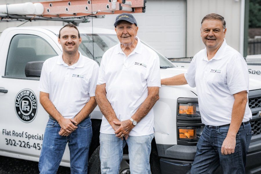 Three men are standing in front of a white truck.