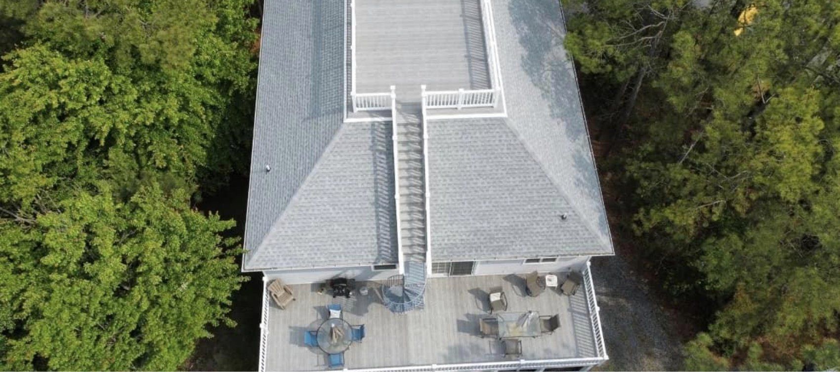 An aerial view of a house with a large deck surrounded by trees.