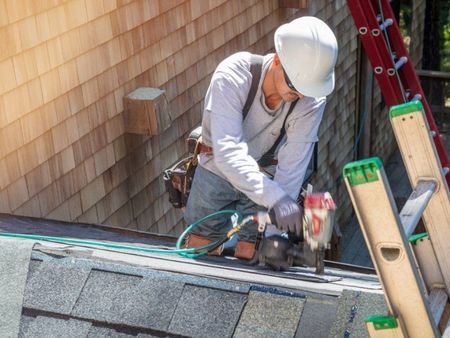 A man is working on the roof of a house.