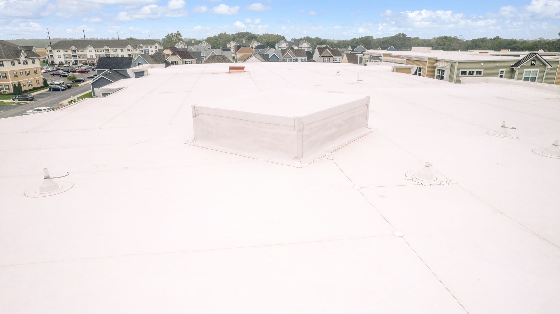 An aerial view of a white roof with a residential area in the background.