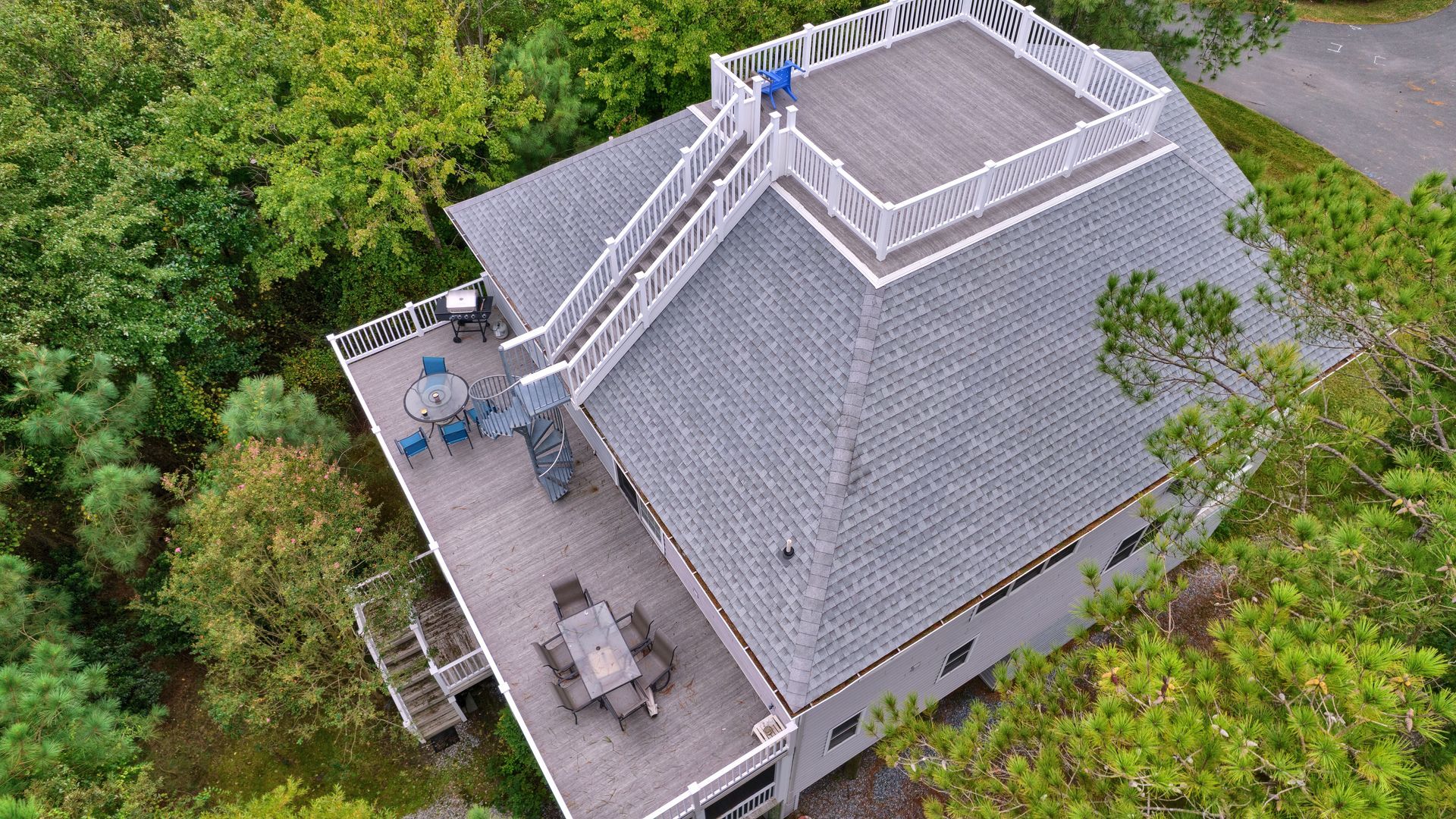 An aerial view of a house with a large deck surrounded by trees.