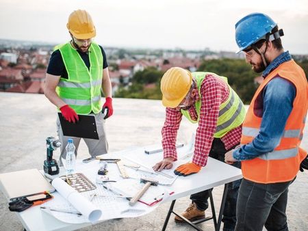 A group of construction workers are standing around a table looking at a blueprint.