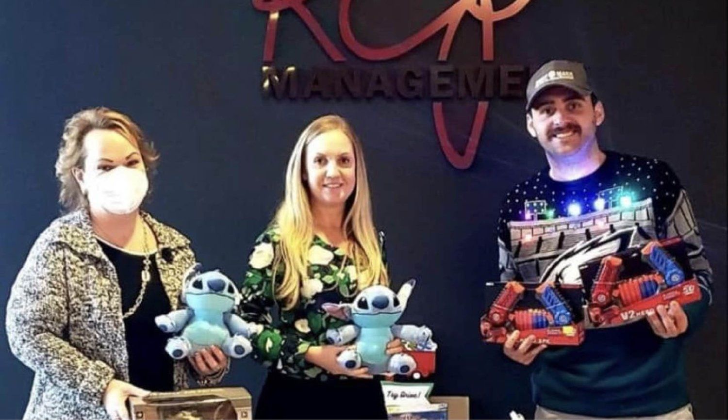 A man and two women are holding stuffed animals in front of a sign that says manageme