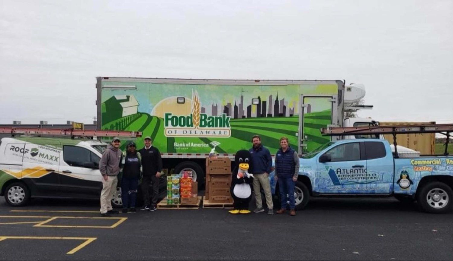 A group of people standing in front of a food bank truck.