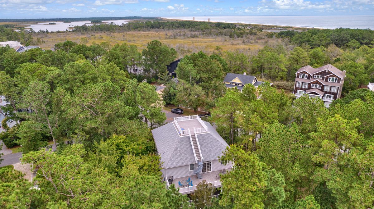 An aerial view of a house surrounded by trees and a body of water.