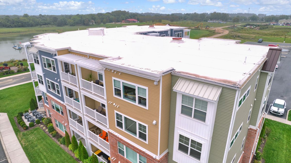 An aerial view of a large apartment building with a white roof.
