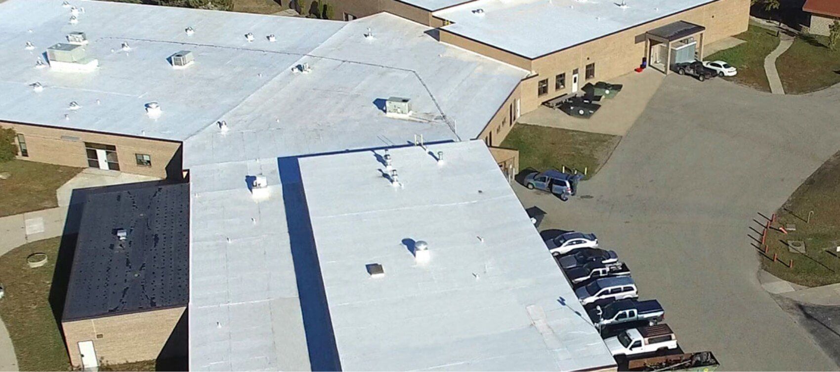 An aerial view of a large building with a white roof