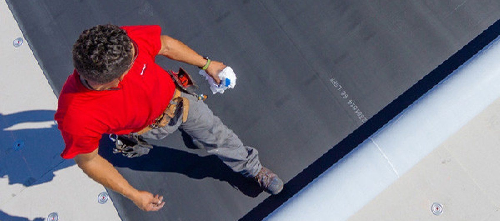 A man in a red shirt is riding a skateboard down a ramp.