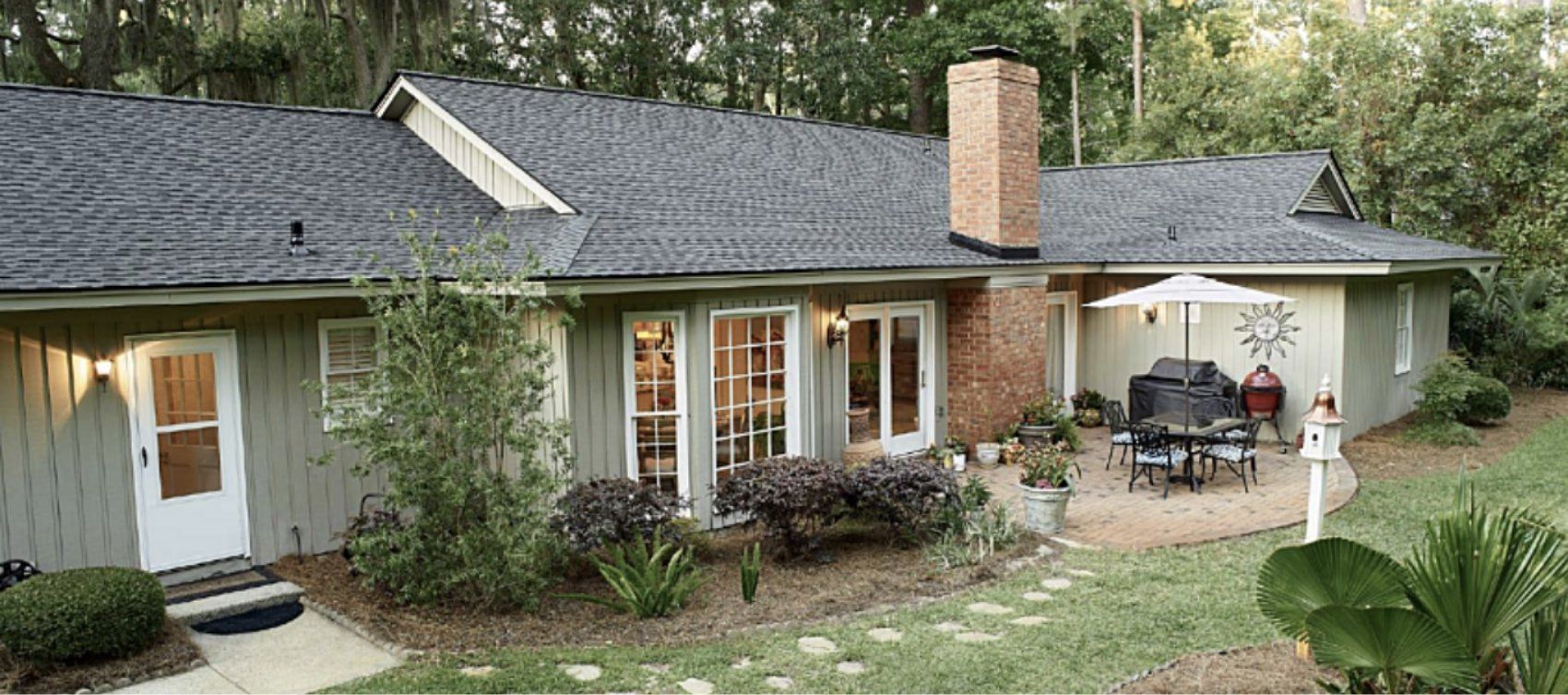 A house with a brick chimney and a patio with a table and chairs.