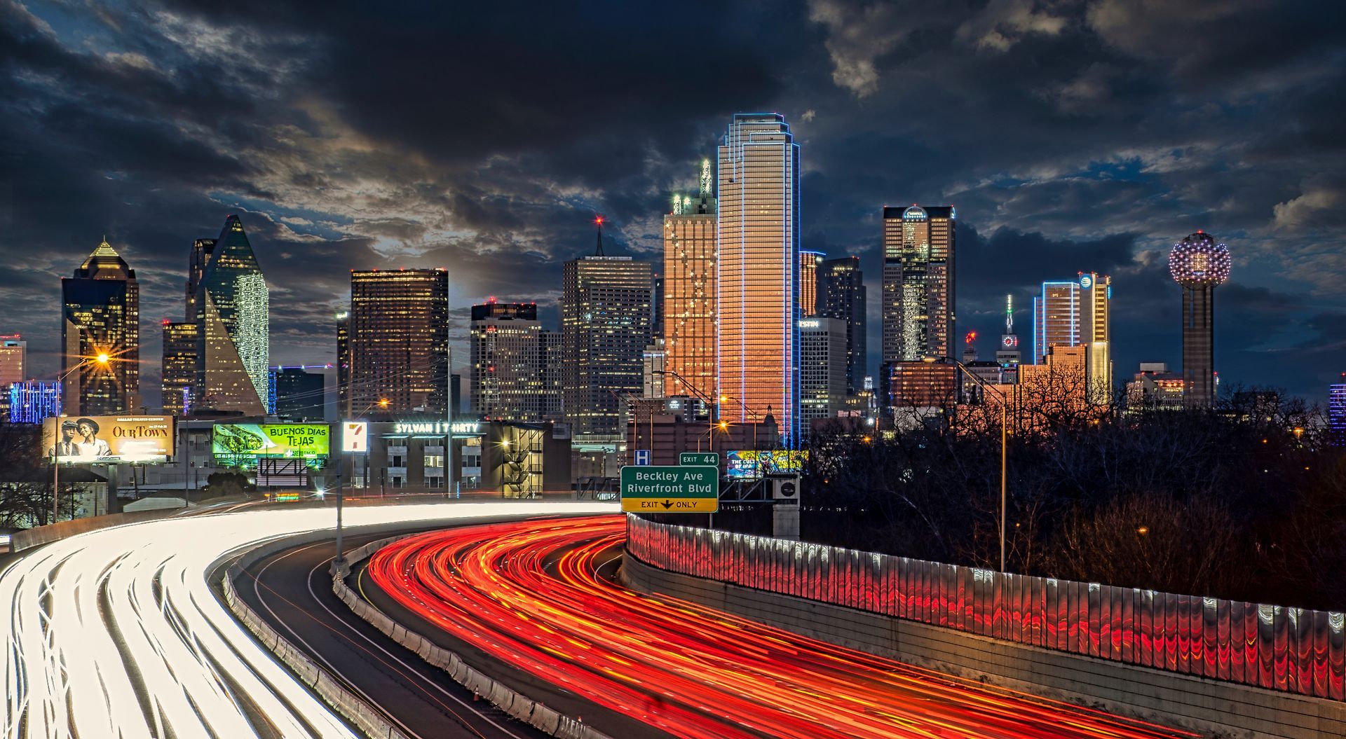 A highway with a city skyline in the background at night.