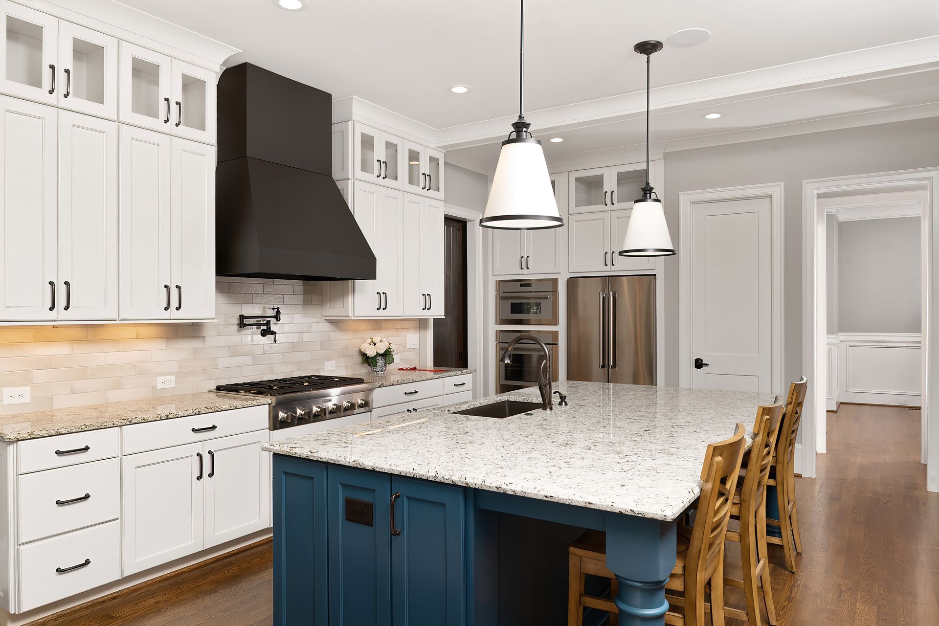 A kitchen with white cabinets and a blue island.