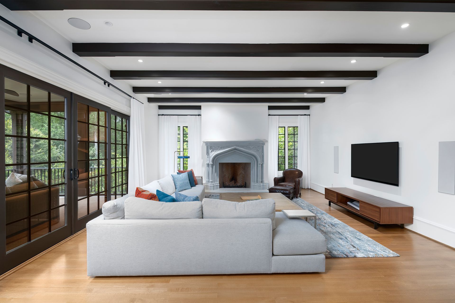 A living room with a couch , fireplace , television and sliding glass doors.