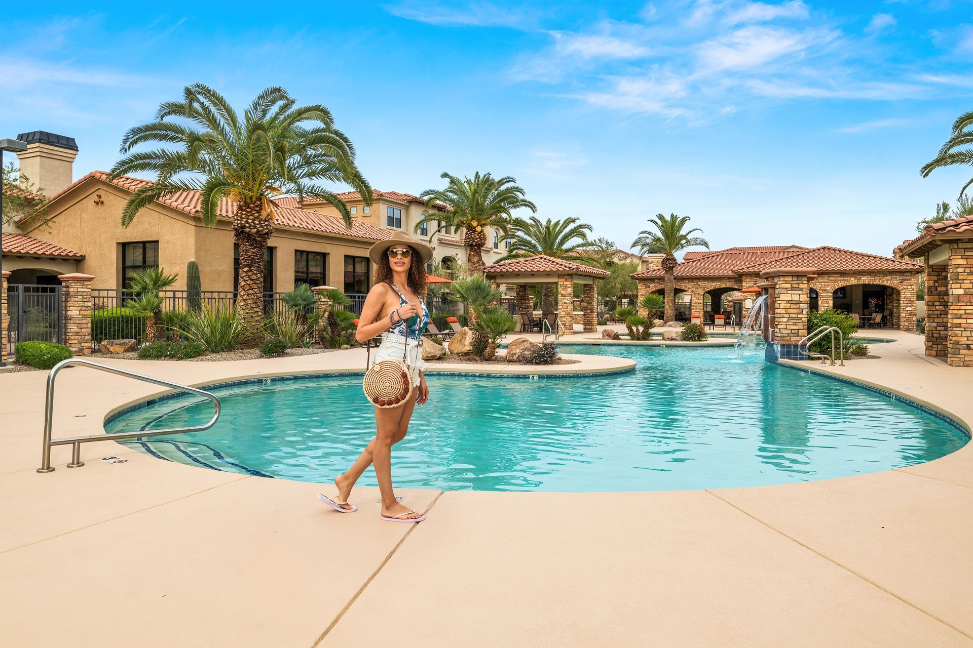 A woman is standing next to a large swimming pool.